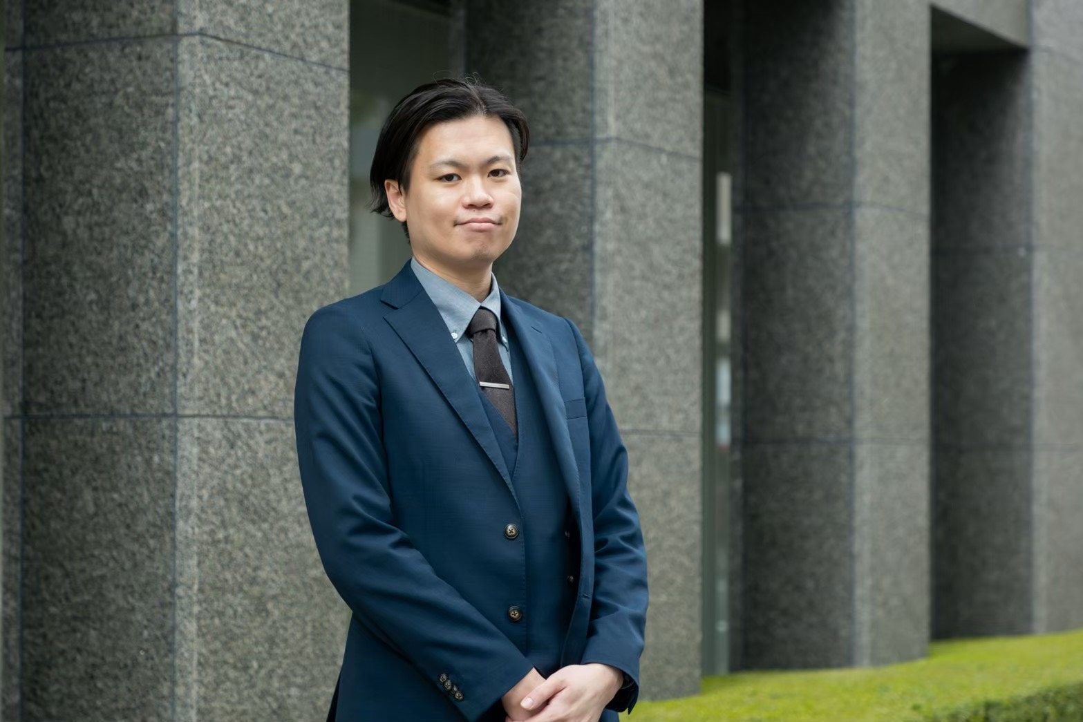 建物を背に立つ河合惇水代表取締役社長